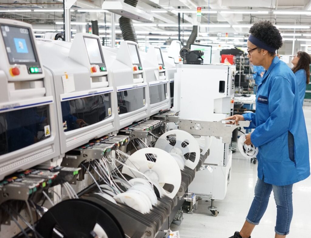 Microboard employee loading a reel of parts into a SMT machine on the production floor. | Join our team image